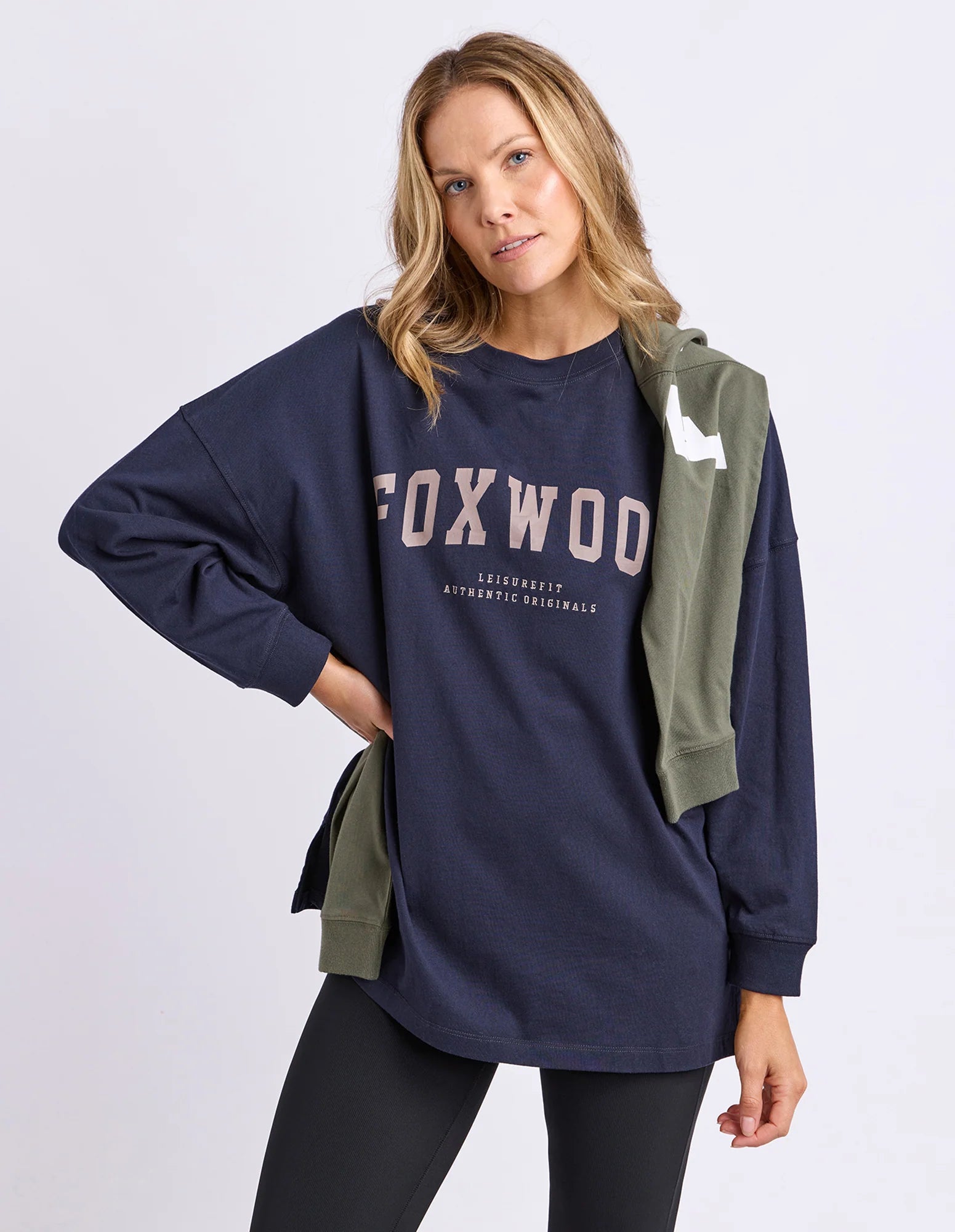 Image of Woman wearing a navy long sleeve tee with 'FOXWOOD' text in brown on a light grey background