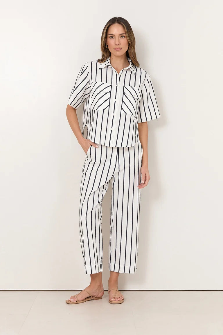 Image of A woman modeling a Adorne matching two-piece set with vertical black stripes on a white background, featuring a short-sleeve button-up shirt and cropped pants.