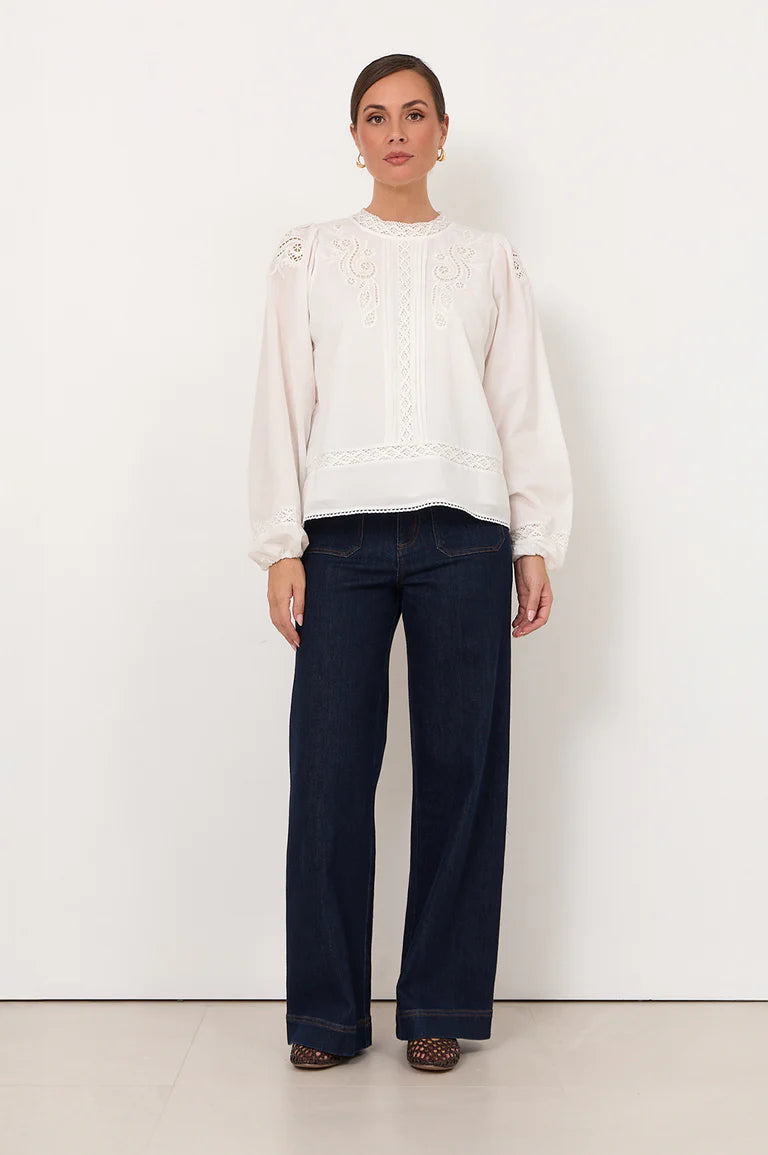 Image of Woman wearing a Adorne white shirt and dark blue jeans against a white background