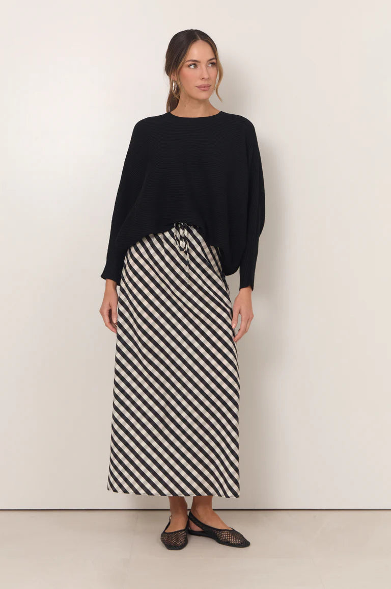 Woman wearing Adorne gingham maxi shirt paired with a black jumper on a plain background 