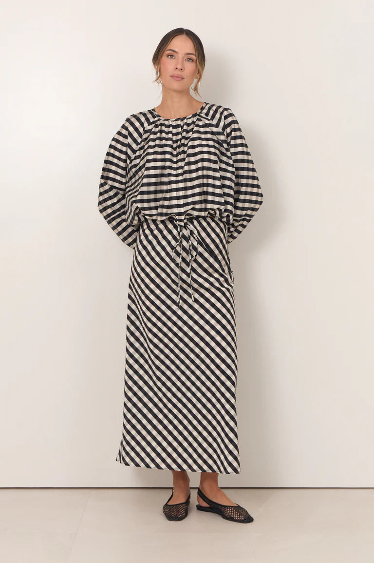 Woman wearing Adorne gingham maxi shirt paired with a matching gingham shirt on a plain background 