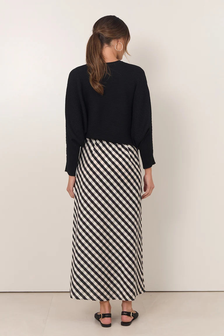 Image of Woman wearing a black top and a long Adorne black and white striped skirt on a plain background