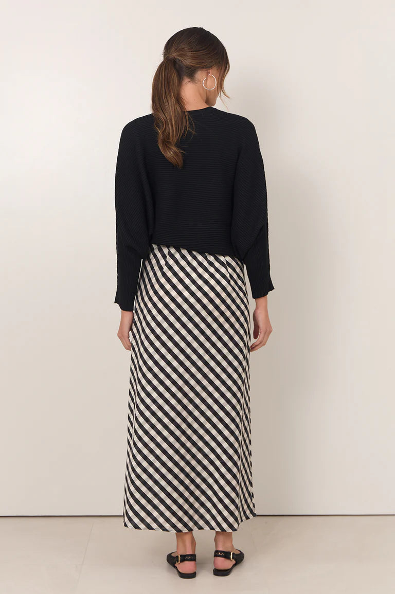 Woman wearing Adorne gingham maxi shirt paired with a black jumper on a plain background 