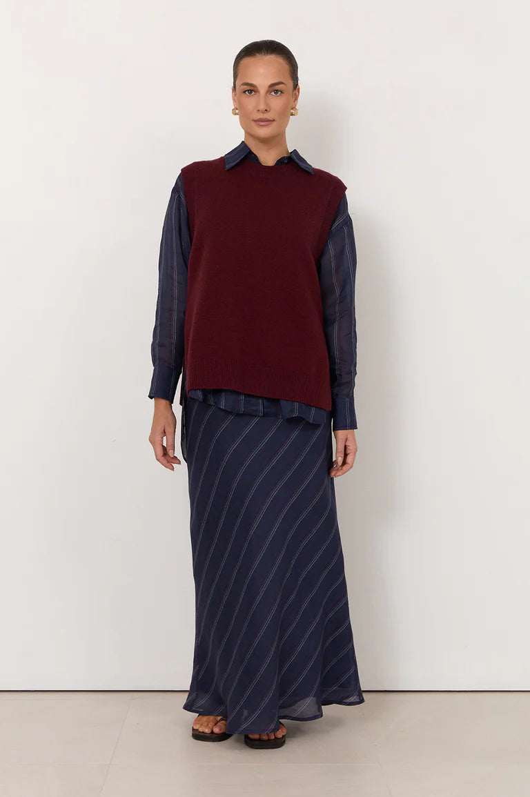 Image of Woman wearing a Adorne burgundy sweater vest over a navy shirt with a long navy skirt on a white background