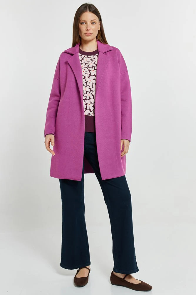Image of Woman wearing a Betty Basics bright pink coat over a patterned top and dark pants on a white background