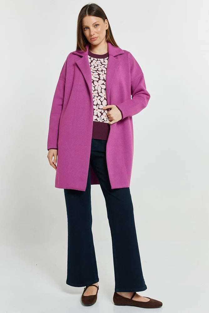 Woman wearing a Betty Basics pink coat over a patterned top on a white background