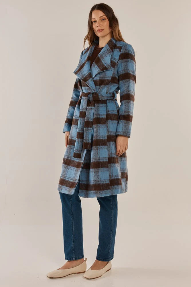 Woman wearing a Betty Basics blue and brown plaid coat against a plain background