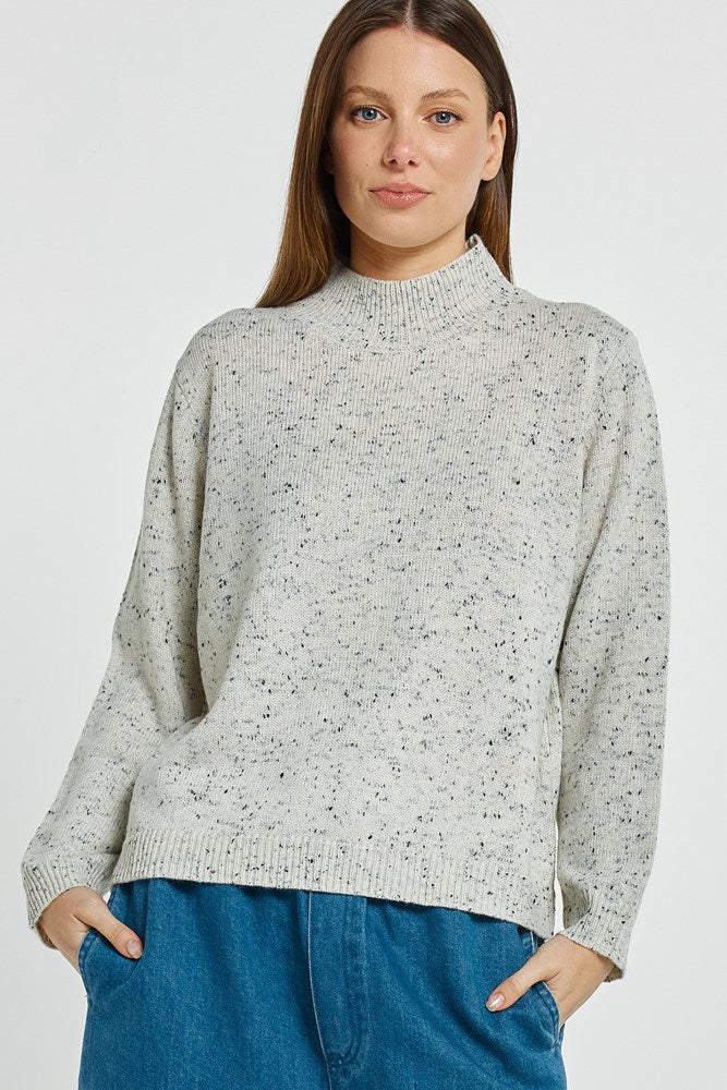 Image of Woman wearing a Betty Basics light gray speckled sweater and blue jeans on a white background