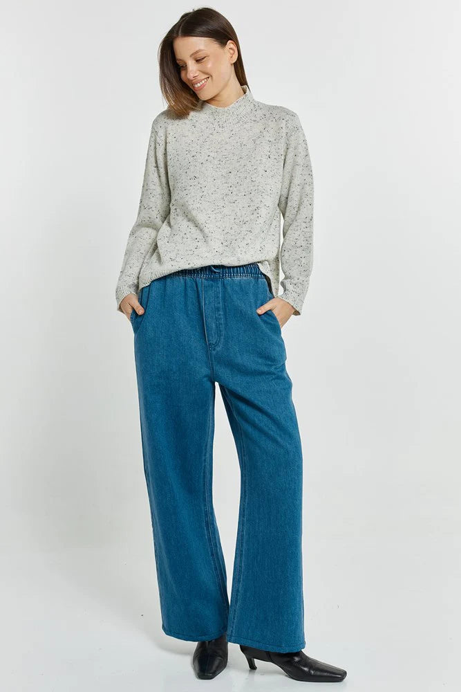 Image of Woman wearing a Betty Basics light gray sweater and blue jeans on a white background