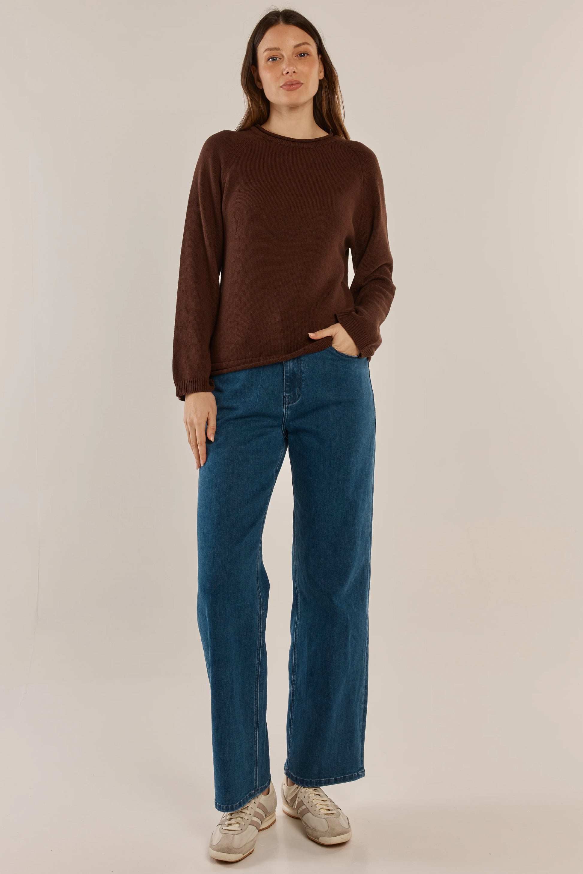 Woman wearing a Betty Basics brown sweater and blue jeans on a beige background