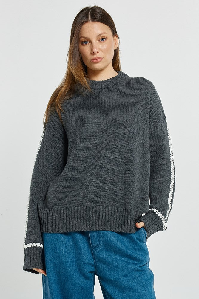 Woman wearing a Betty Basics dark gray sweater with white trim on a light gray background