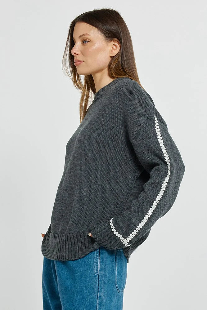 Image of Woman wearing a Betty Basics dark gray sweater with white zipper details on a light gray background