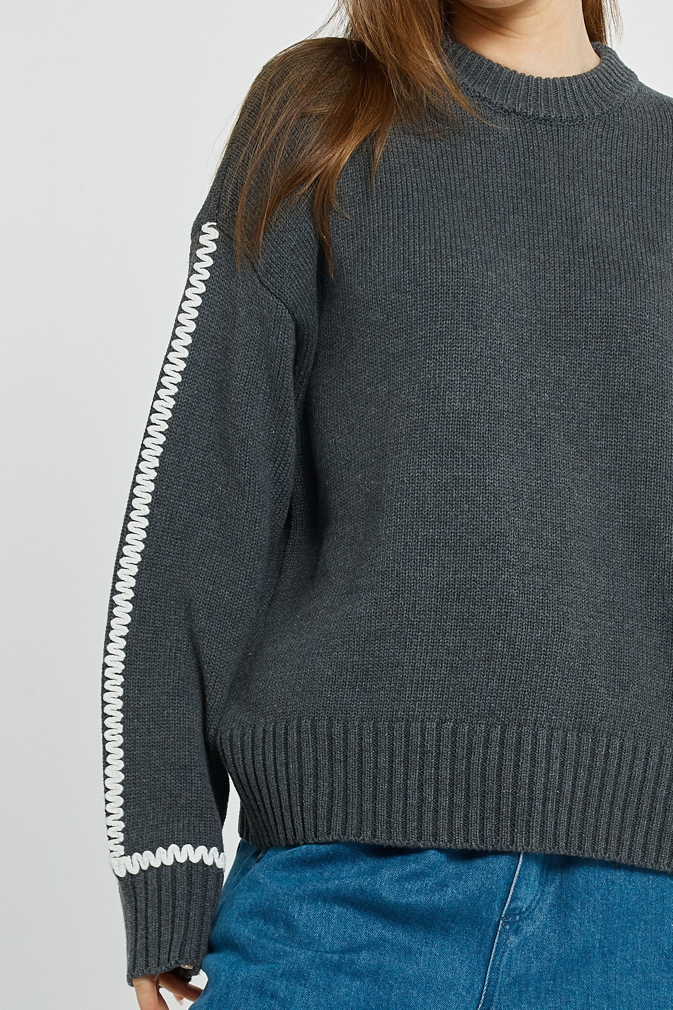 Betty Basics grey sweater with white zipper details worn by a woman on a light grey background