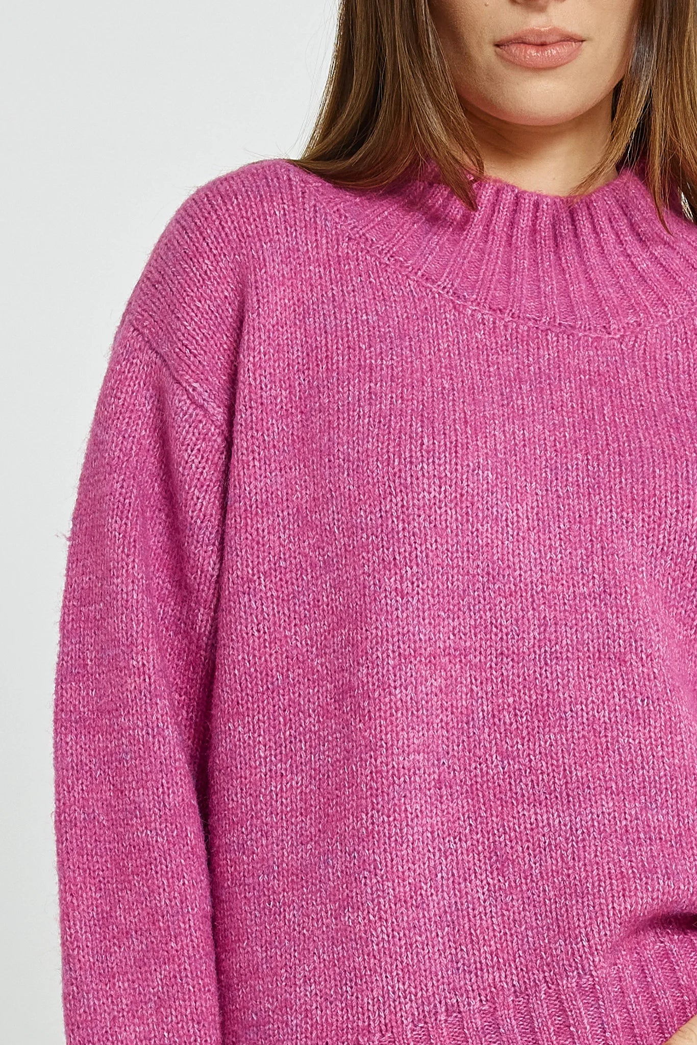 Image of Close-up of a Betty Basics pink knitted sweater worn by a woman.