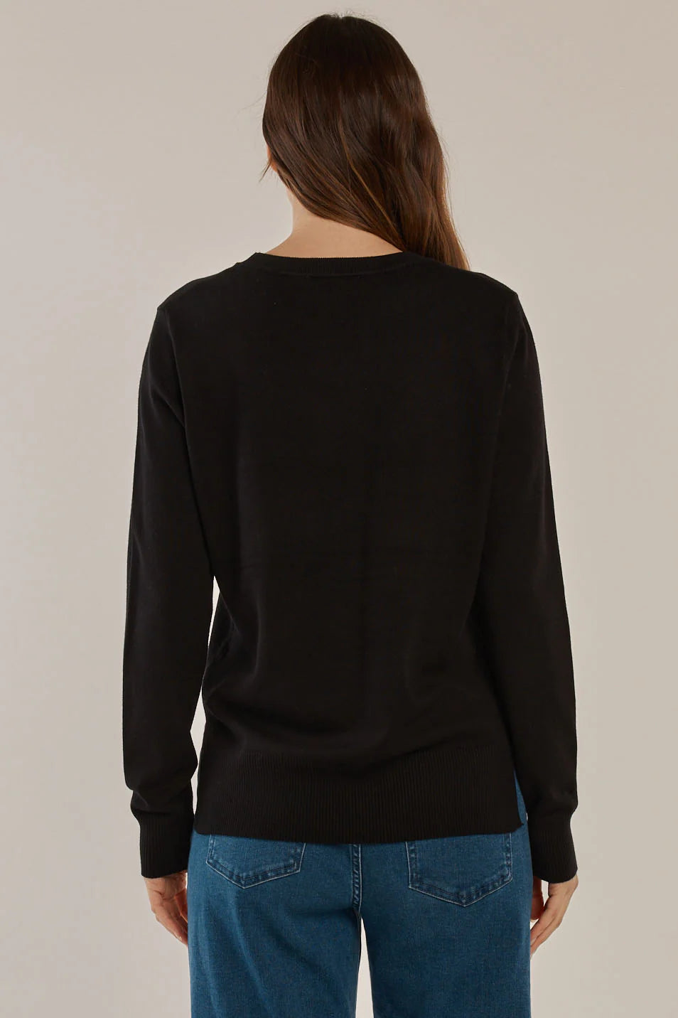 Image of Woman wearing a black sweater and blue jeans against a plain background
