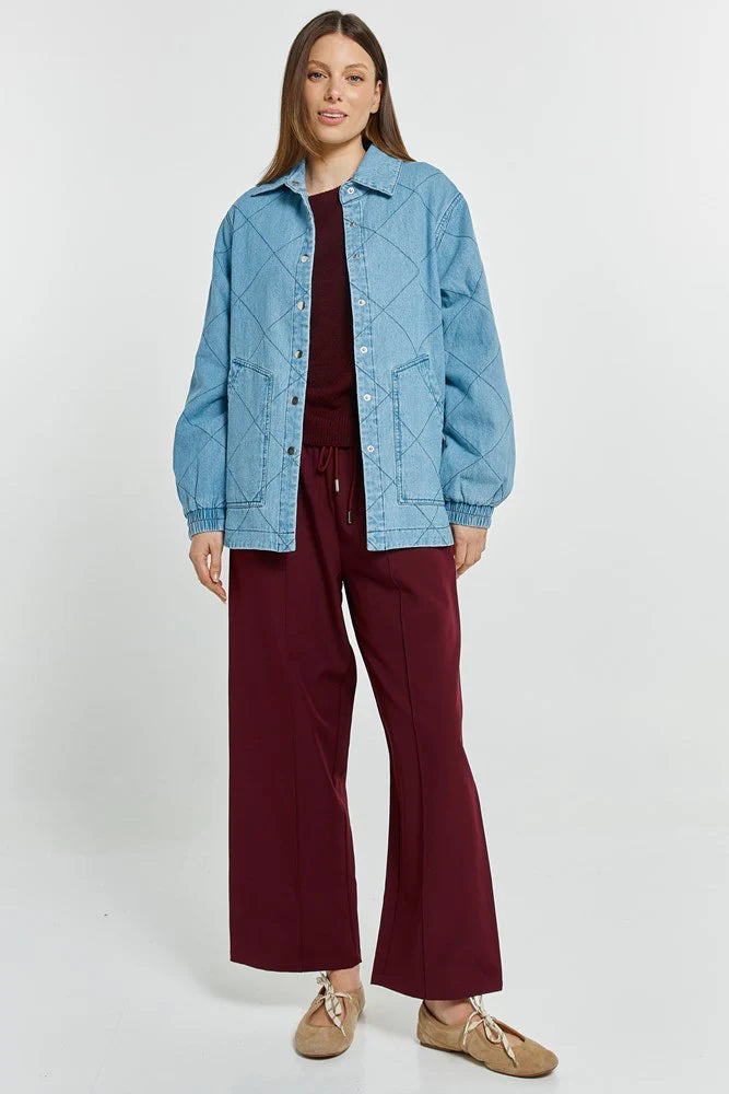 Image of Woman wearing a Betty Basics blue denim jacket and burgundy pants on a white background