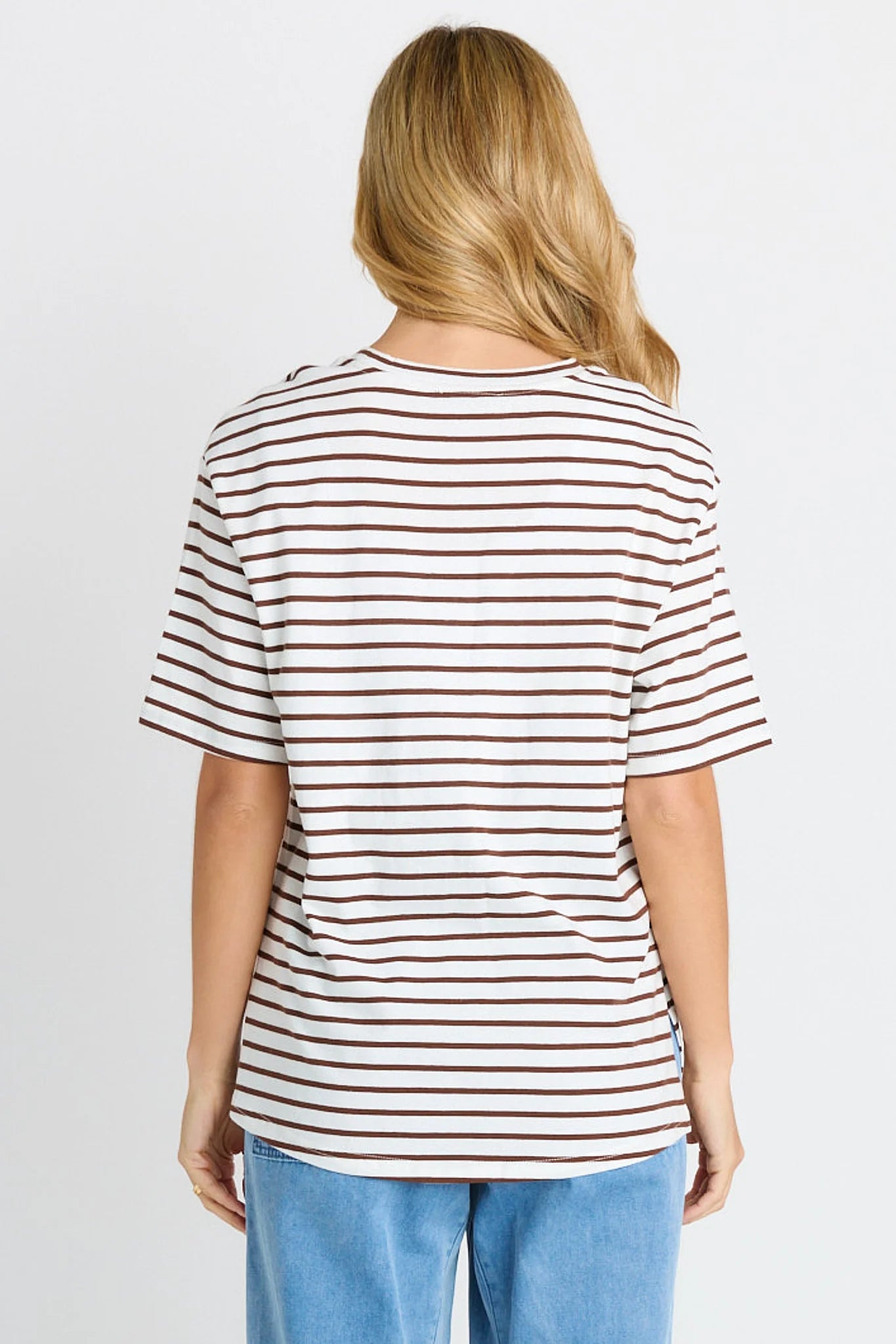 Woman wearing a Betty Basics striped t-shirt and blue jeans on a plain background