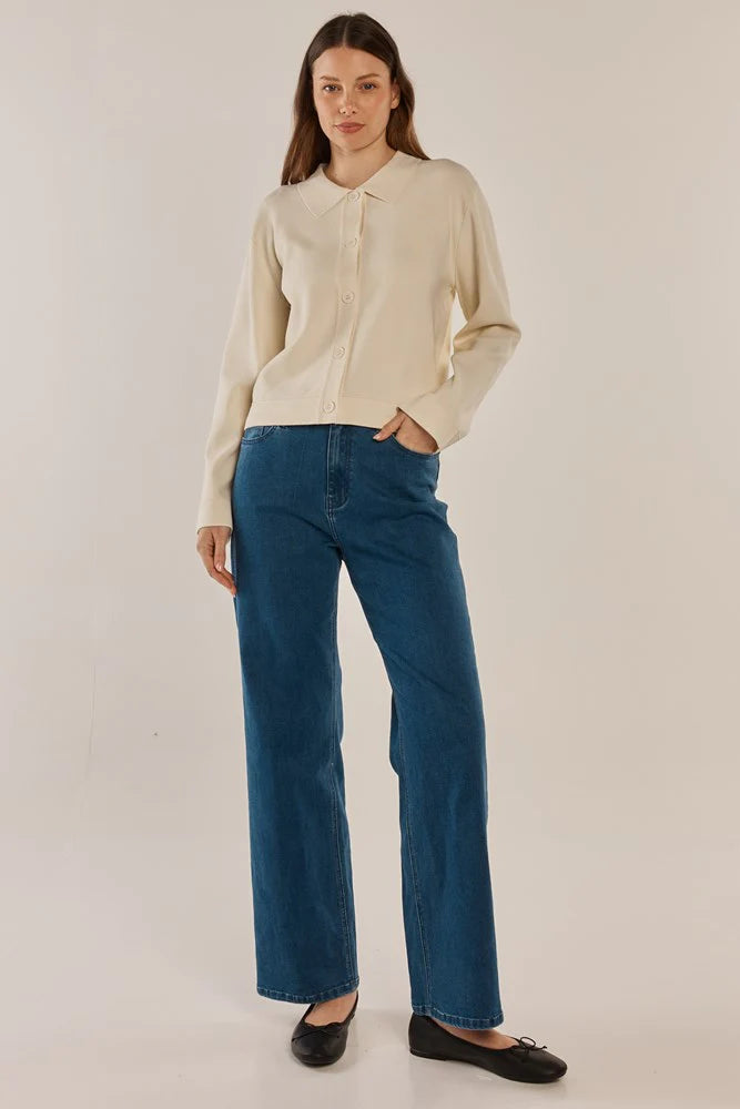 Woman wearing a Betty Basics beige blouse and blue jeans on a plain background