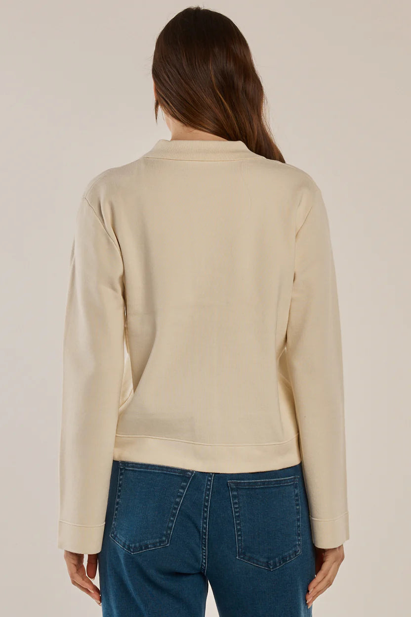 Image of Woman wearing a Betty Basics beige knit and blue jeans on a plain background