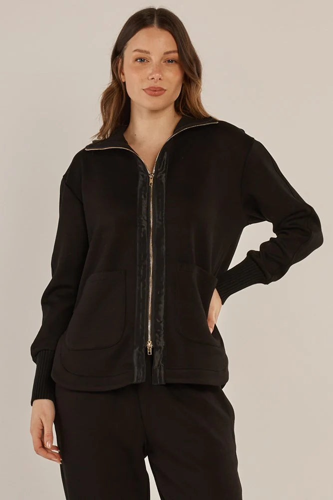 Image of Woman wearing a Betty Basics black zip-up hoodie on a beige background