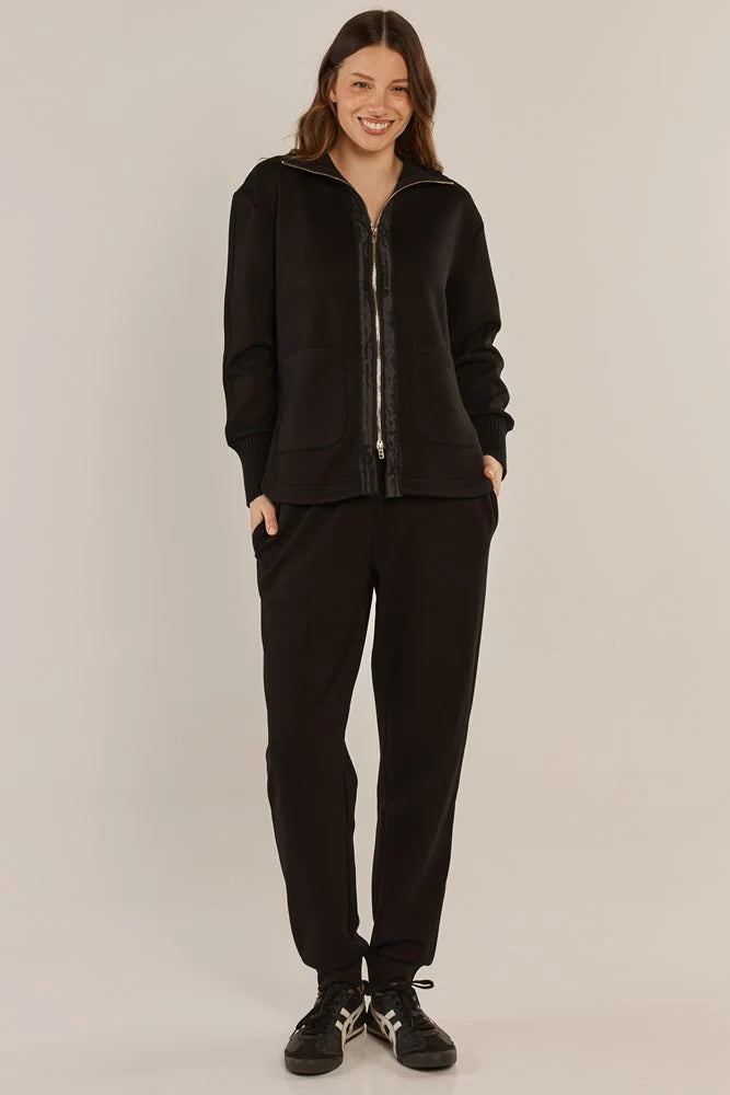 Image of Woman wearing a Betty Basics lack zip-up hoodie and pants on a beige background