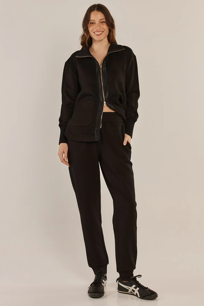 Woman wearing a Betty Basics black tracksuit on a plain background