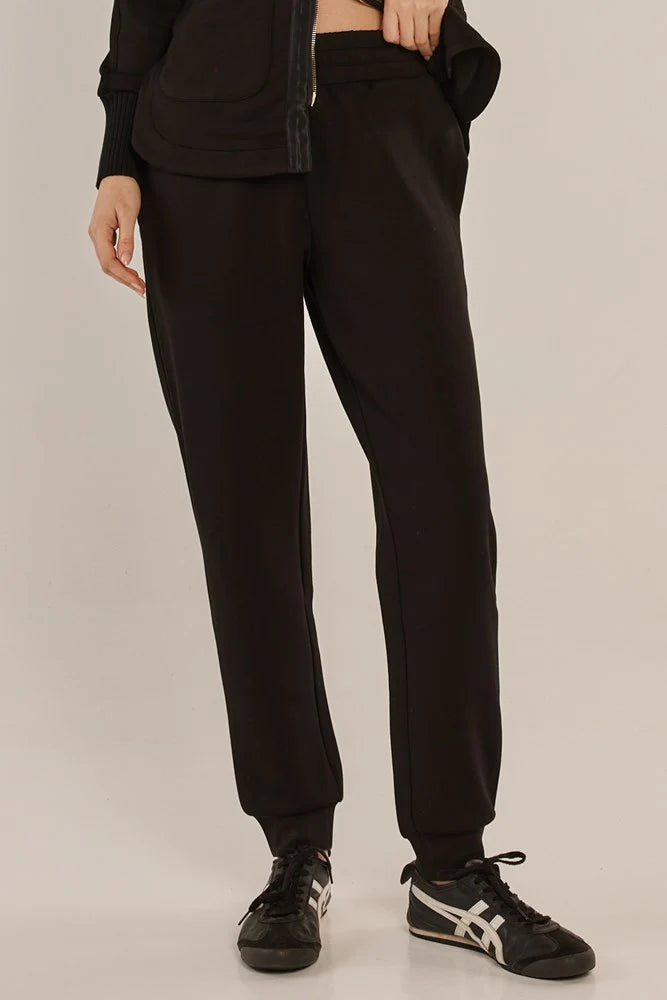 Image of Woman wearing Betty Basics black jogger pants on a plain background