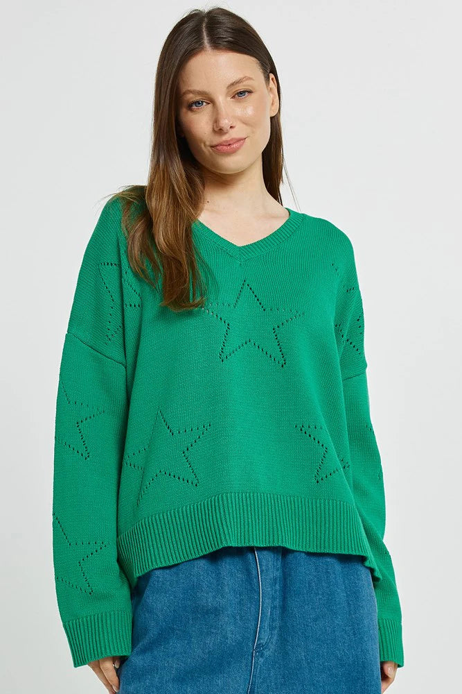 Woman wearing a Betty Basics green sweater with star patterns on a white background