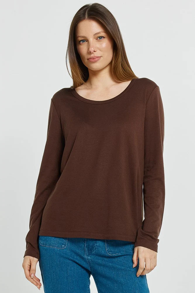 Woman wearing a Betty Basics brown long-sleeve top and blue jeans on a white background