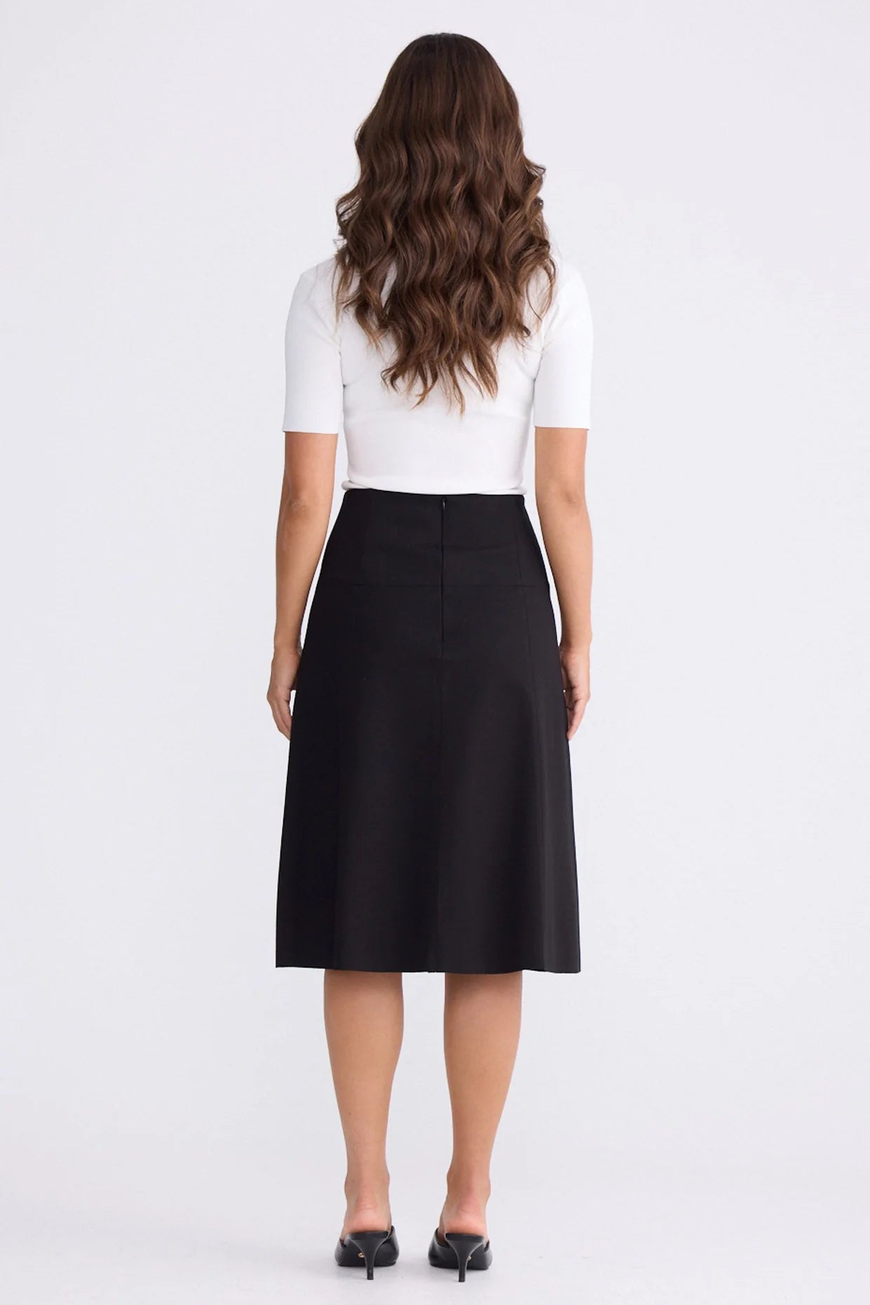 Woman wearing a white top and Brave & True black skirt on a white background