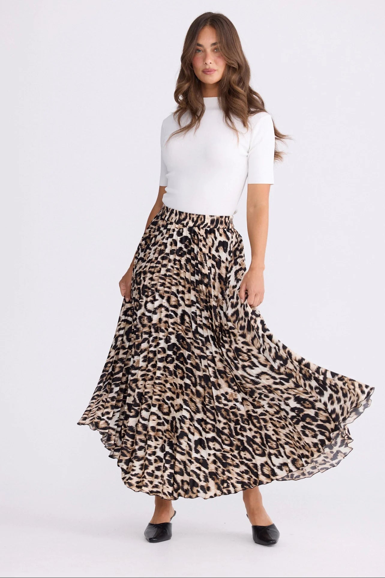 Woman wearing a white top and Brave and True leopard print skirt on a white background