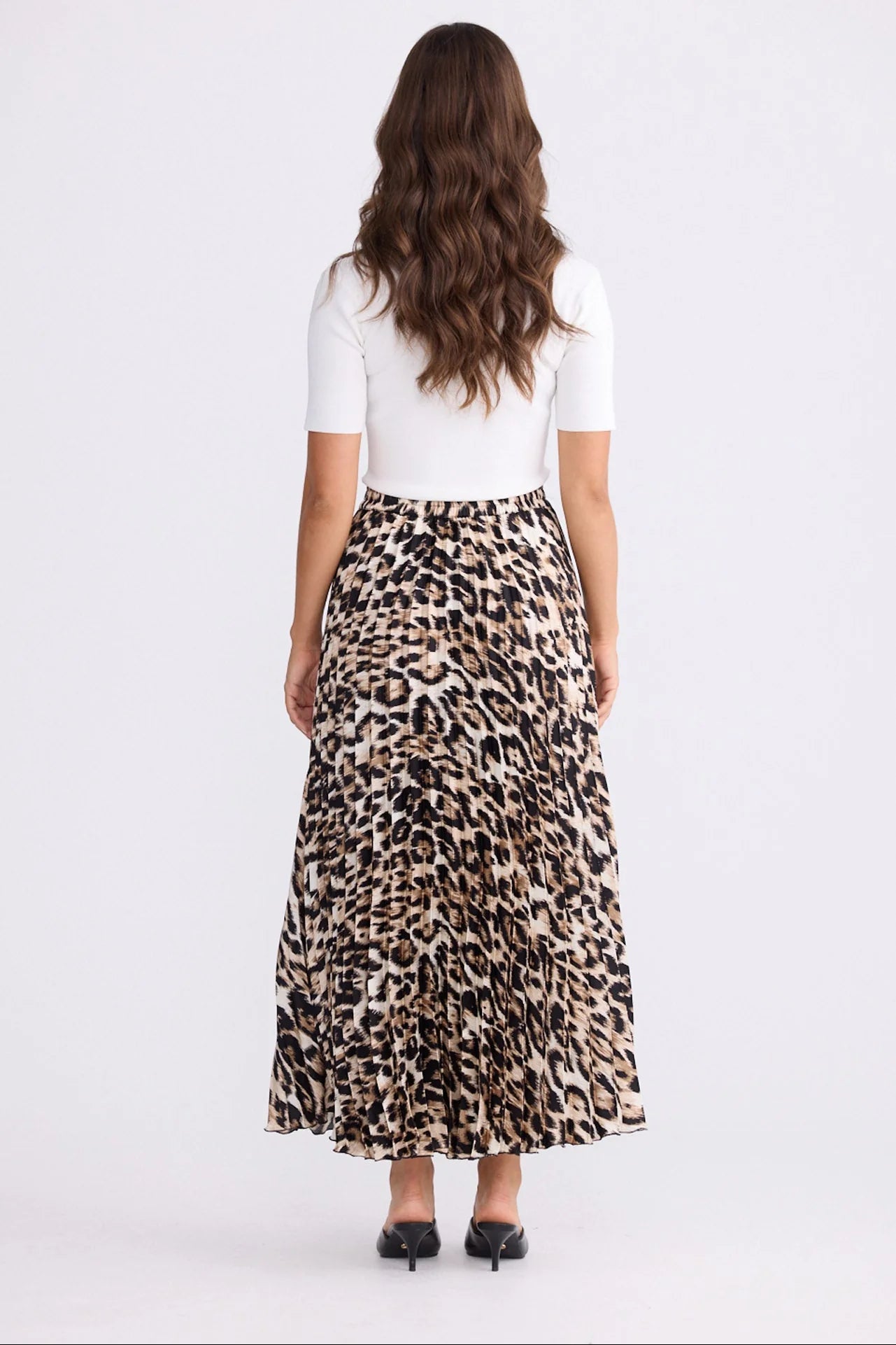 Woman wearing a white top and Brave and True leopard print skirt on a white background