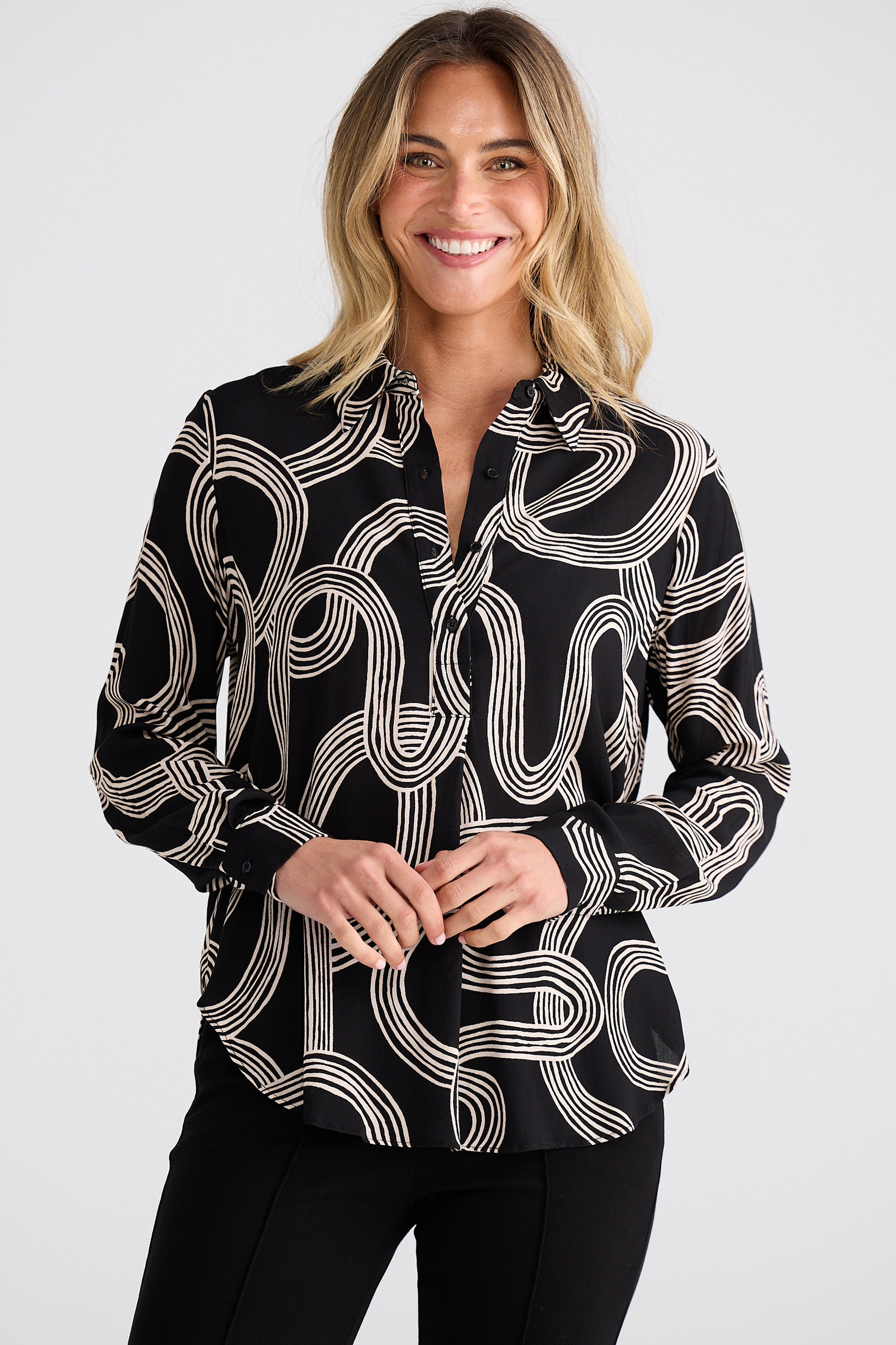 Woman wearing a Brave and True black and white patterned blouse against a white background