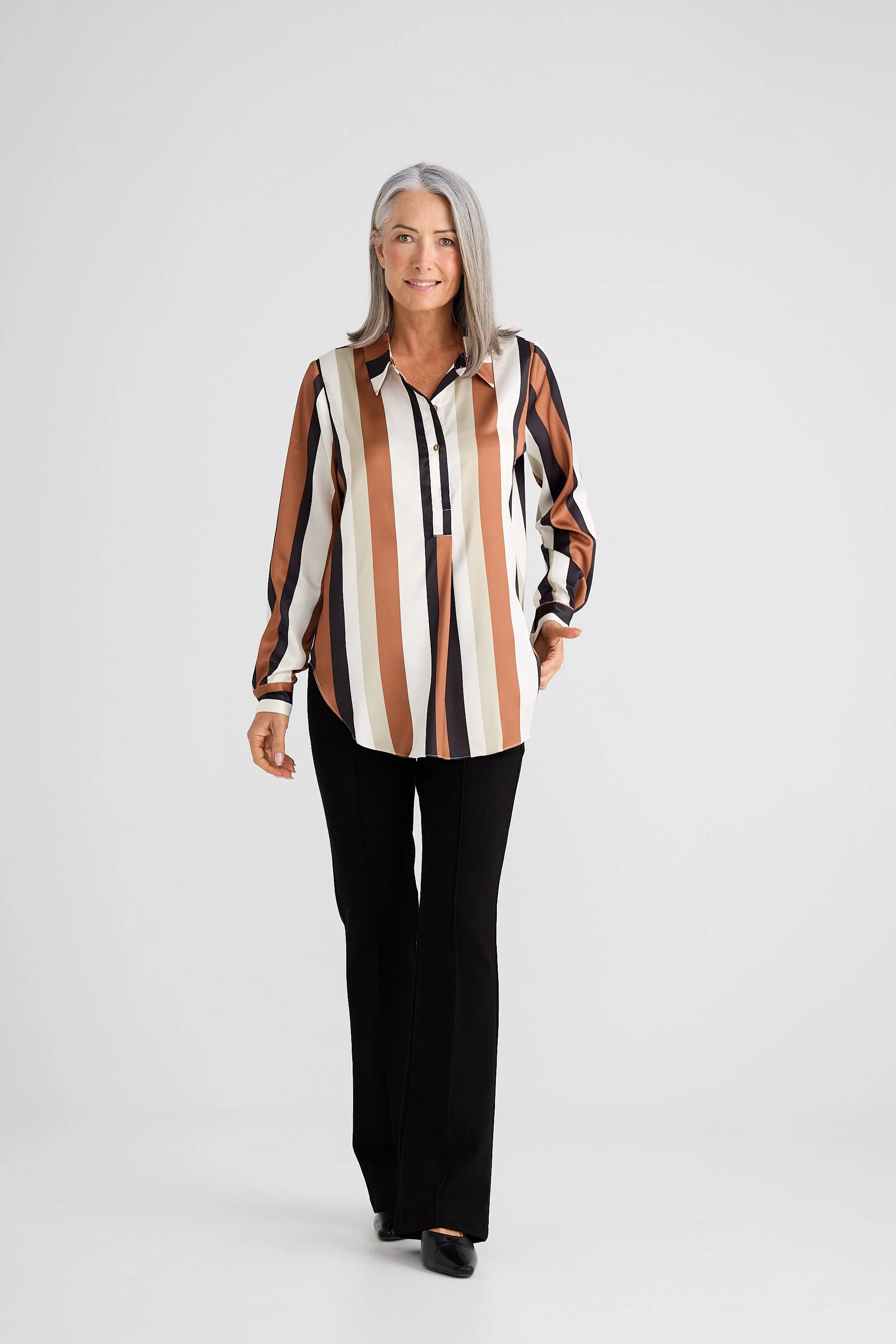 Woman wearing a Brave & True striped shirt and black pants on a white background