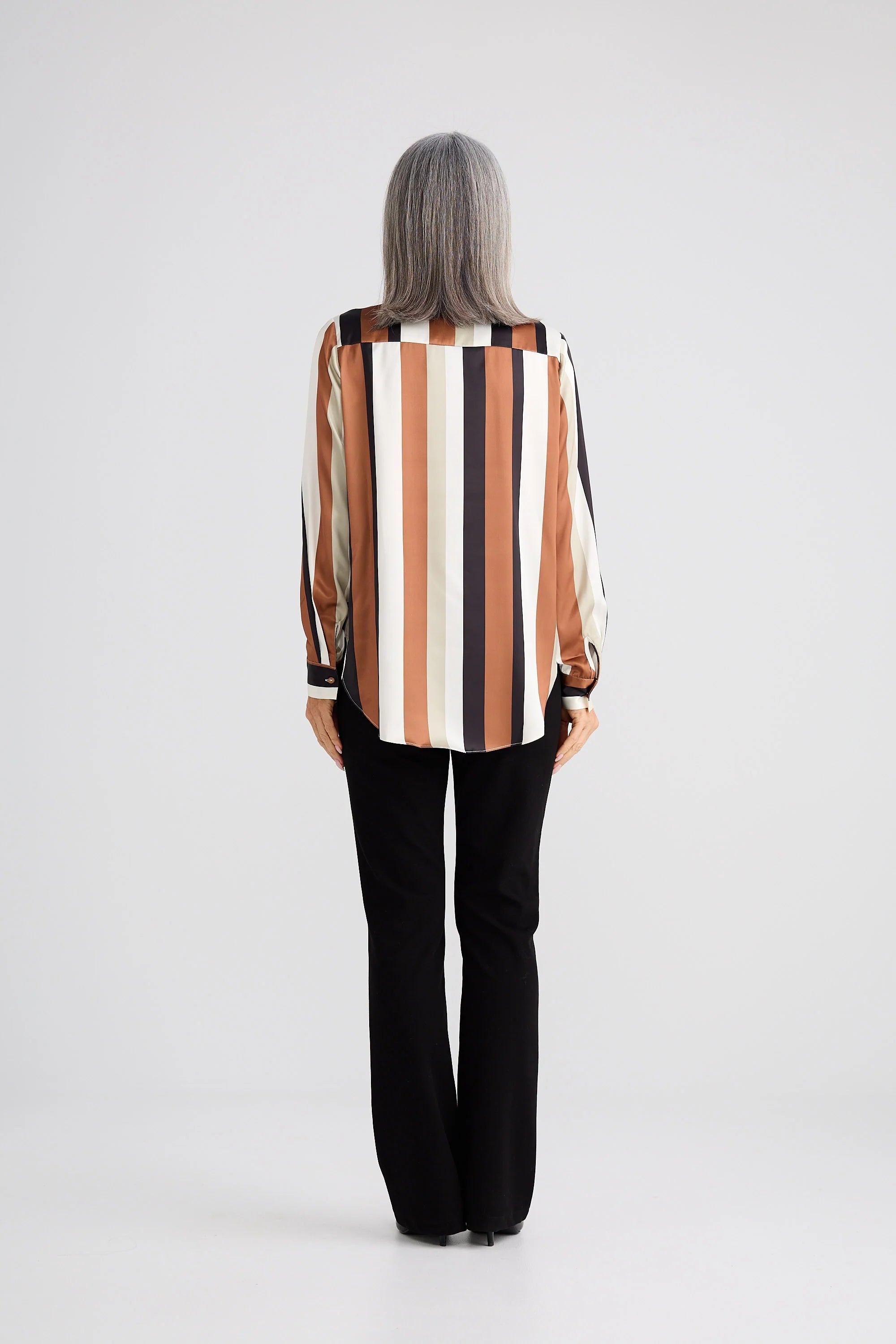 Image of Woman wearing a Brave and True striped shirt and black pants on a white background
