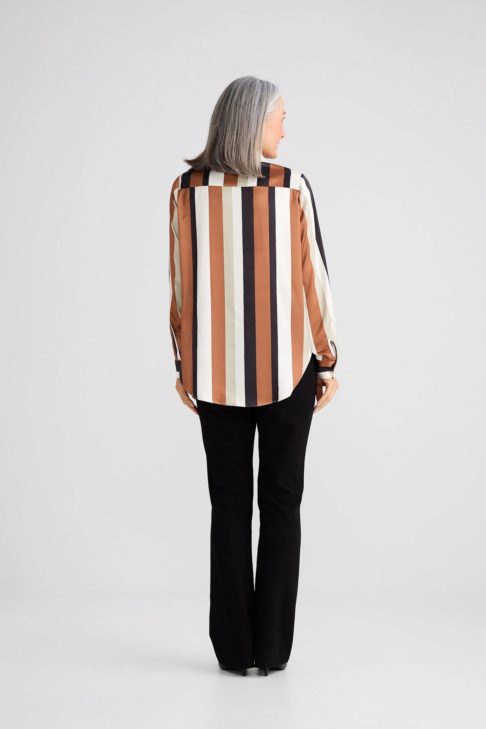 Woman wearing a Brave and True striped shirt and black pants on a white background