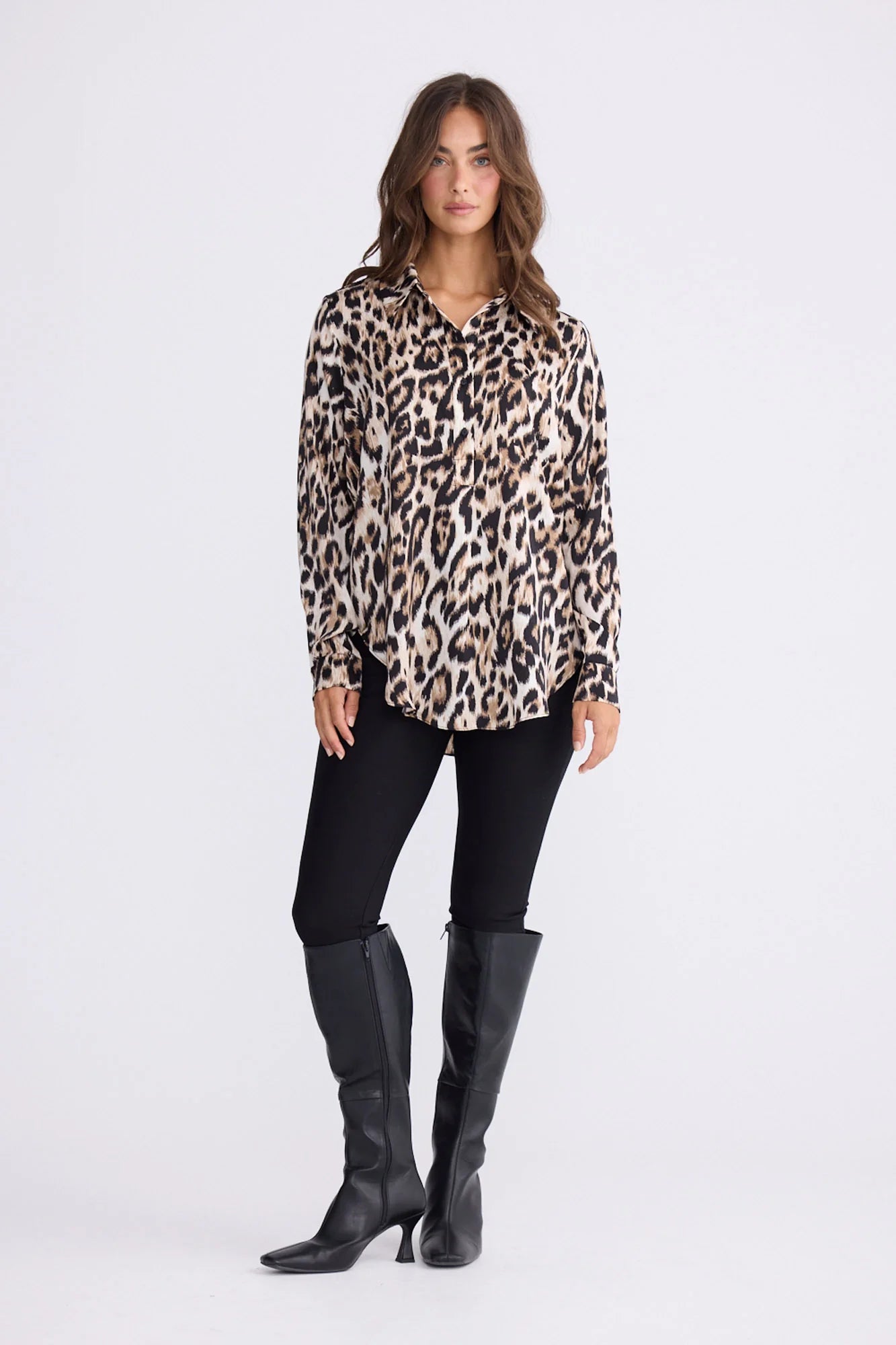 Image of Woman wearing a Brave and True leopard print blouse, black leggings, and black knee-high boots on a white background