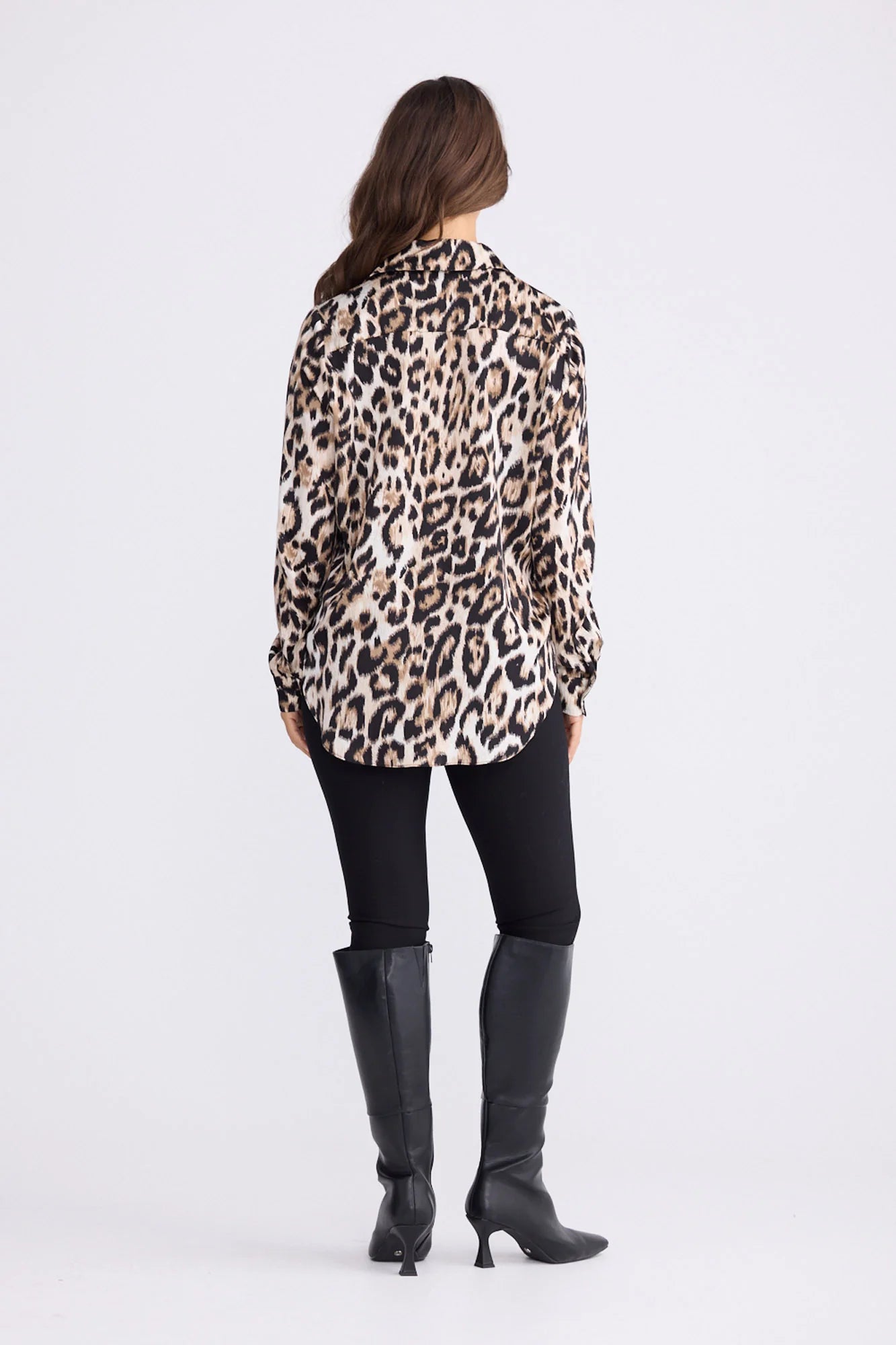 Image of Woman wearing a Brave and True leopard print shirt and black pants with gray boots on a white background