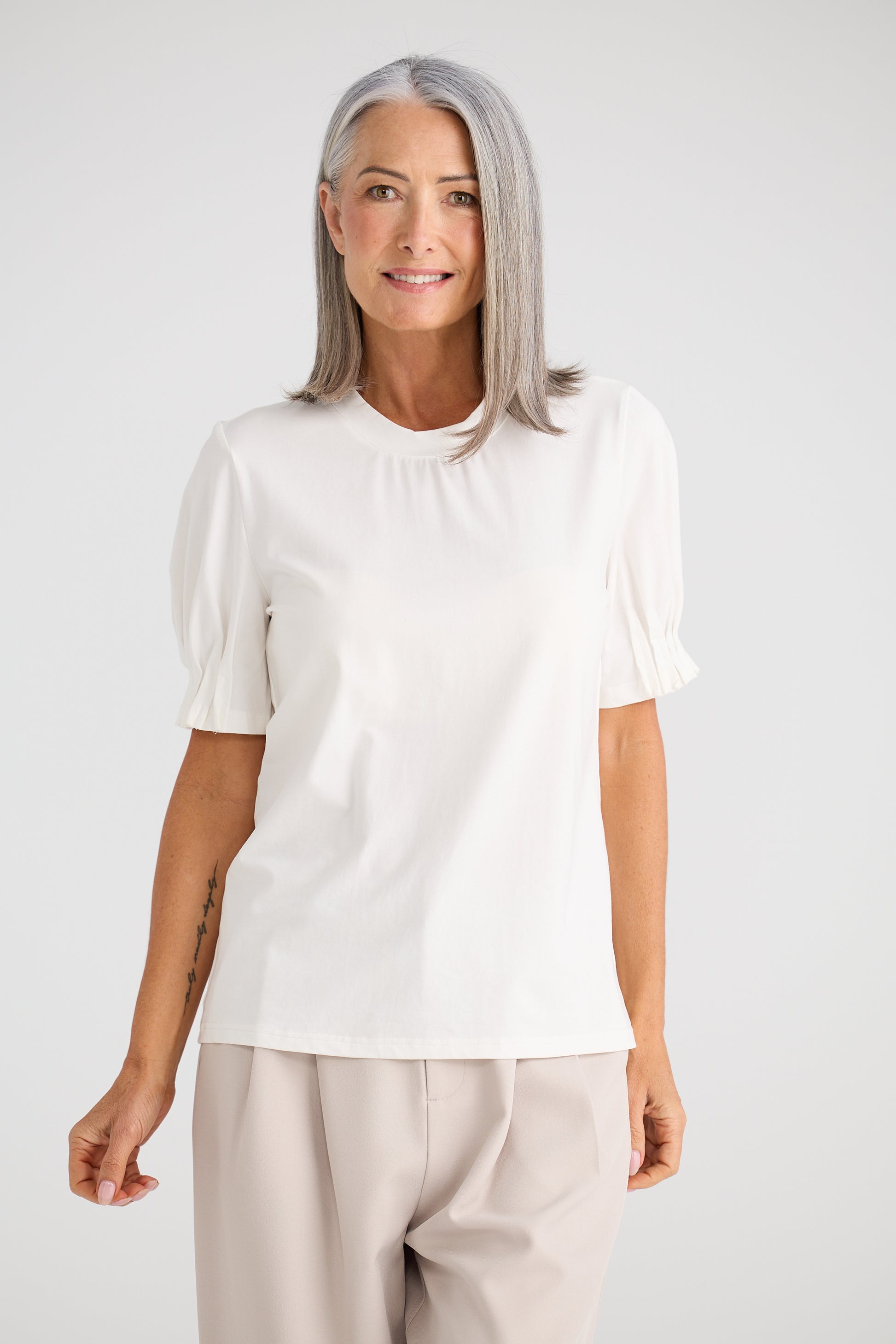 Woman wearing a Brave and True white blouse with puff sleeves against a plain background