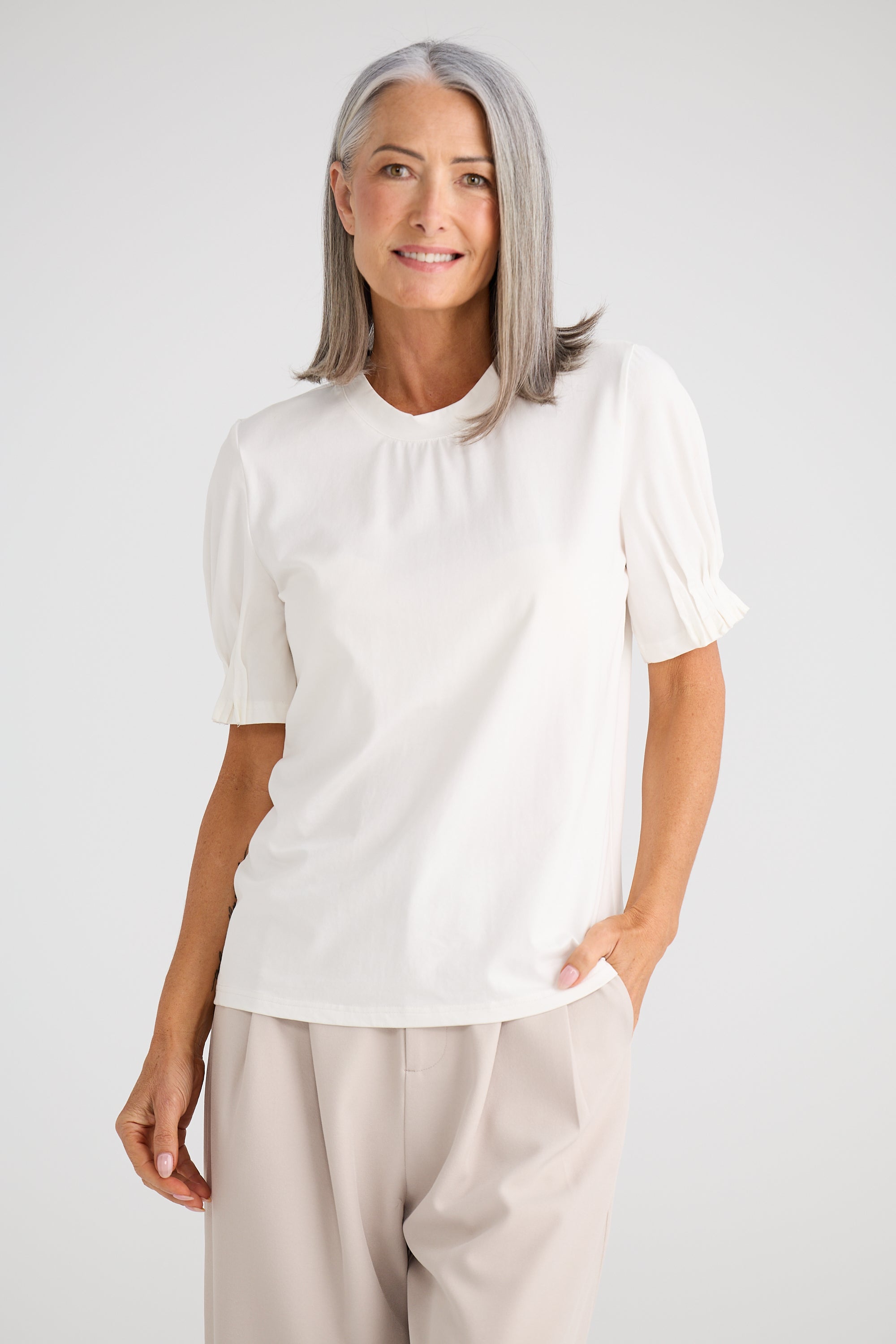 Collection of Woman wearing a Brave and True white blouse and beige pants against a plain background in a gallery layout