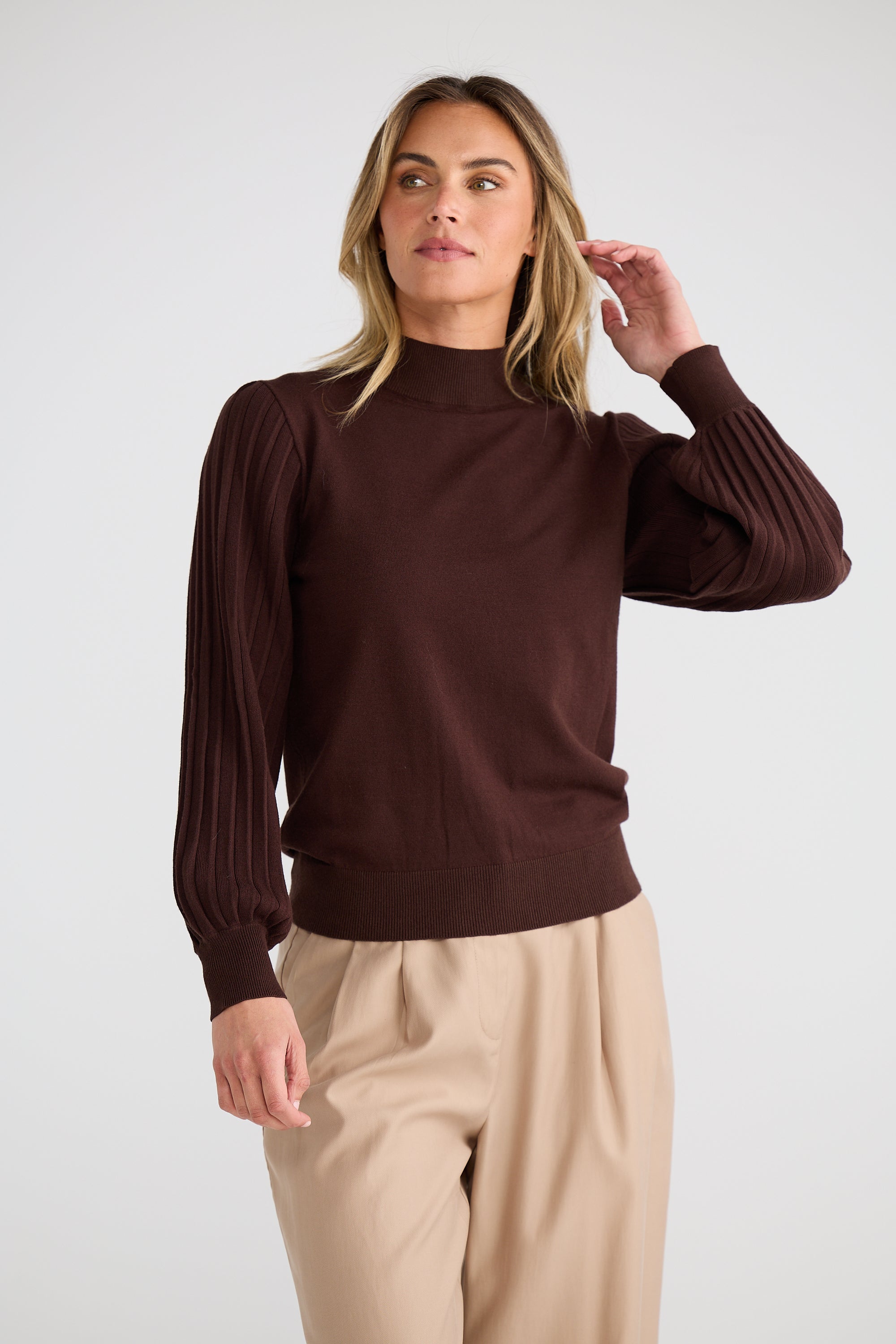 Image of Woman wearing a Brave and True brown sweater and beige pants against a white background