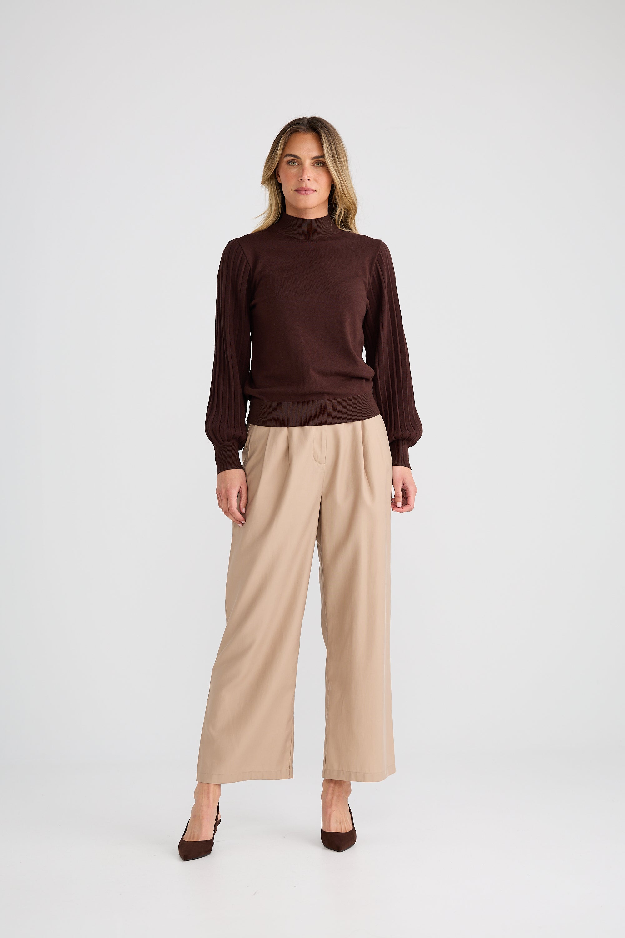 Image of Woman wearing a Brave & True brown sweater and beige pants on a white background