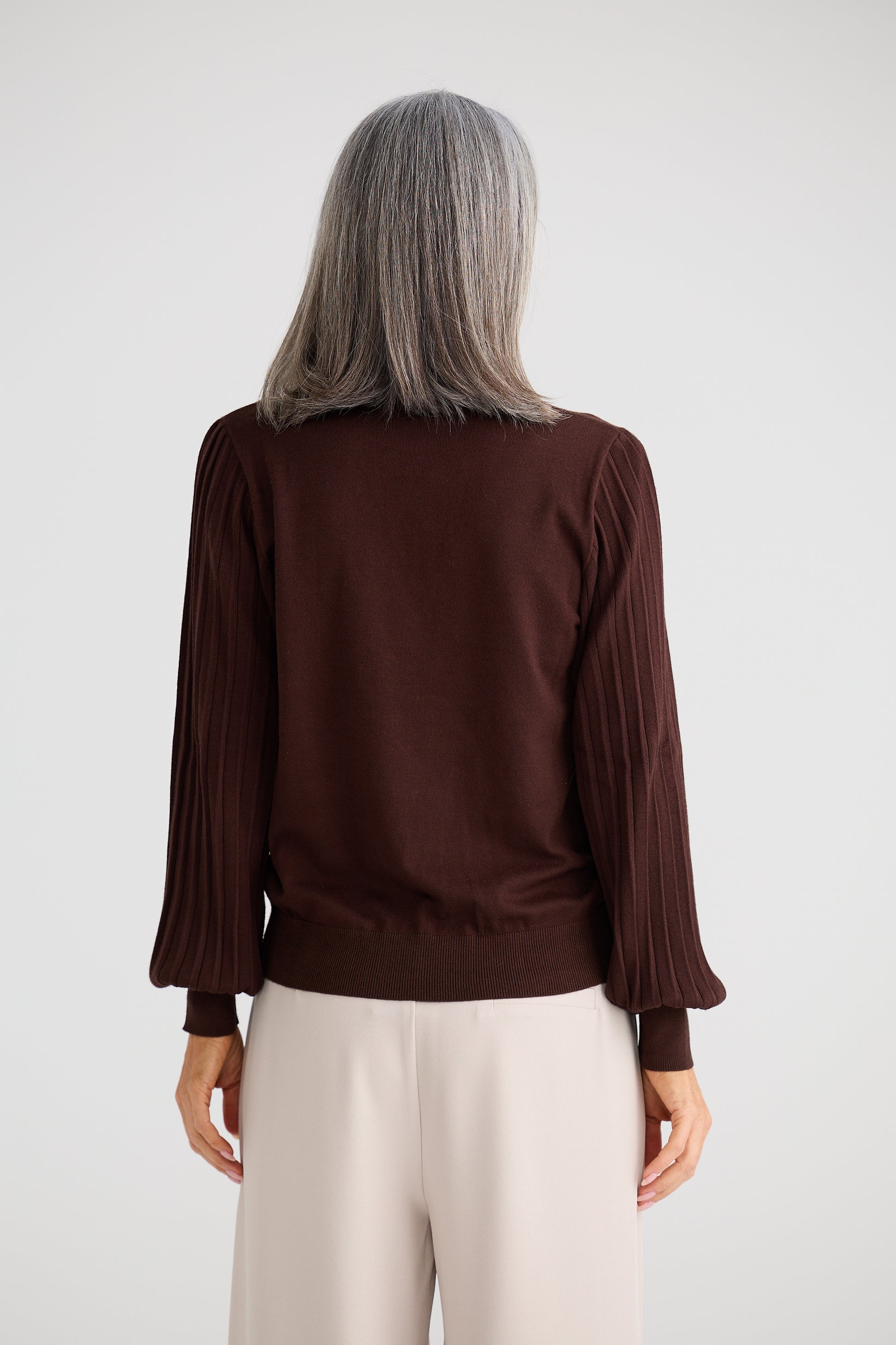 Woman wearing a Brave & True brown blouse with long sleeves on a white background