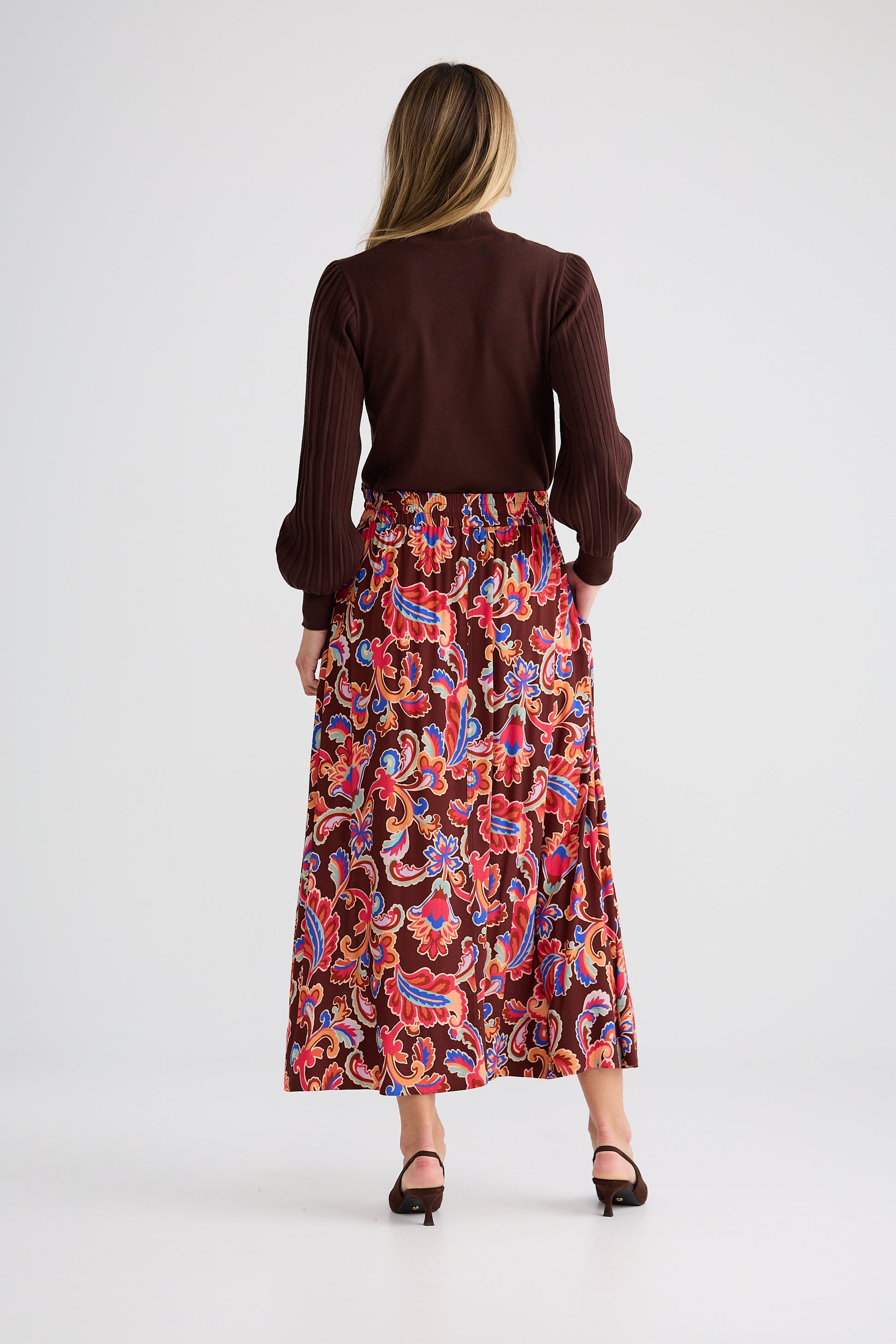 Woman wearing a brown blouse and Brave and True colorful paisley skirt on a white background