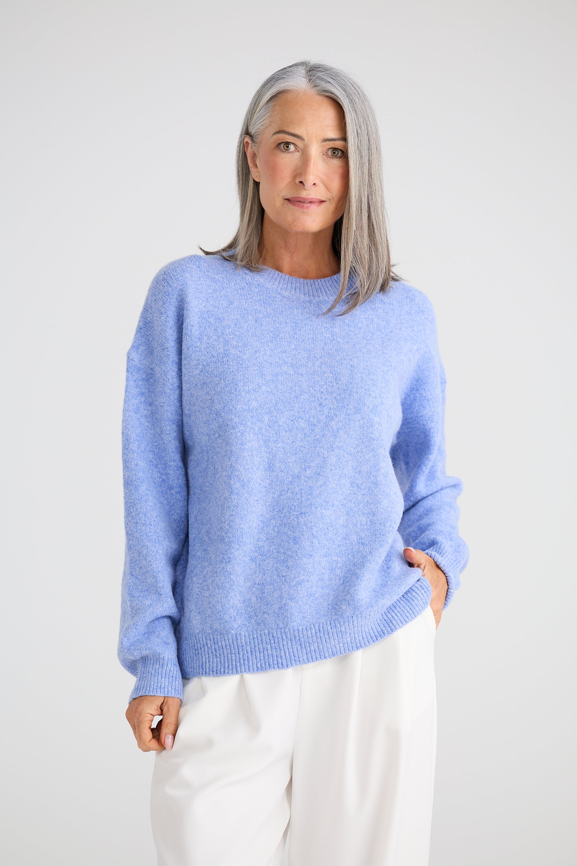 Woman wearing a Brave and True light blue sweater against a white background