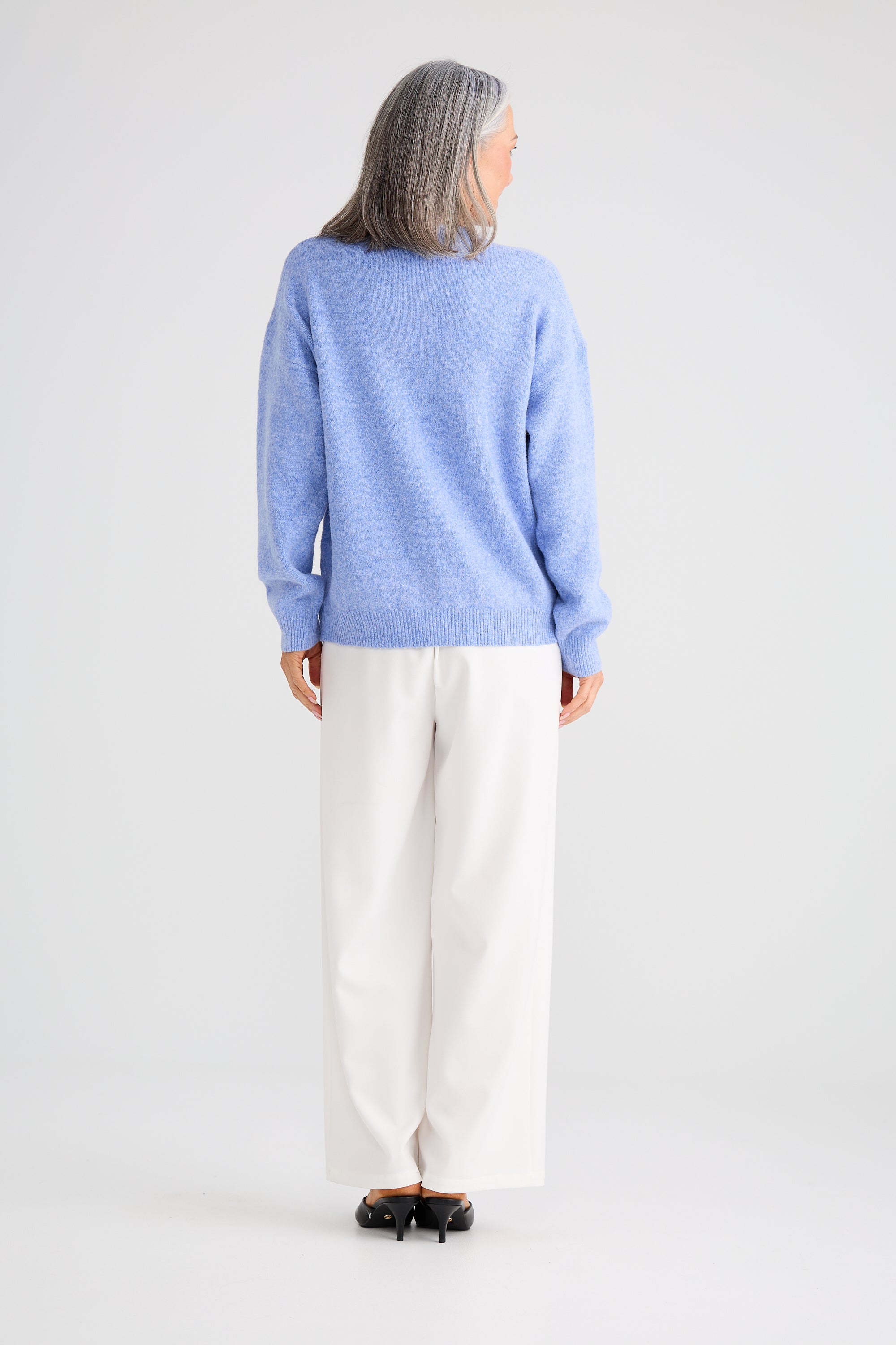 Image of Woman wearing a Brave and True light blue sweater and white pants on a plain background