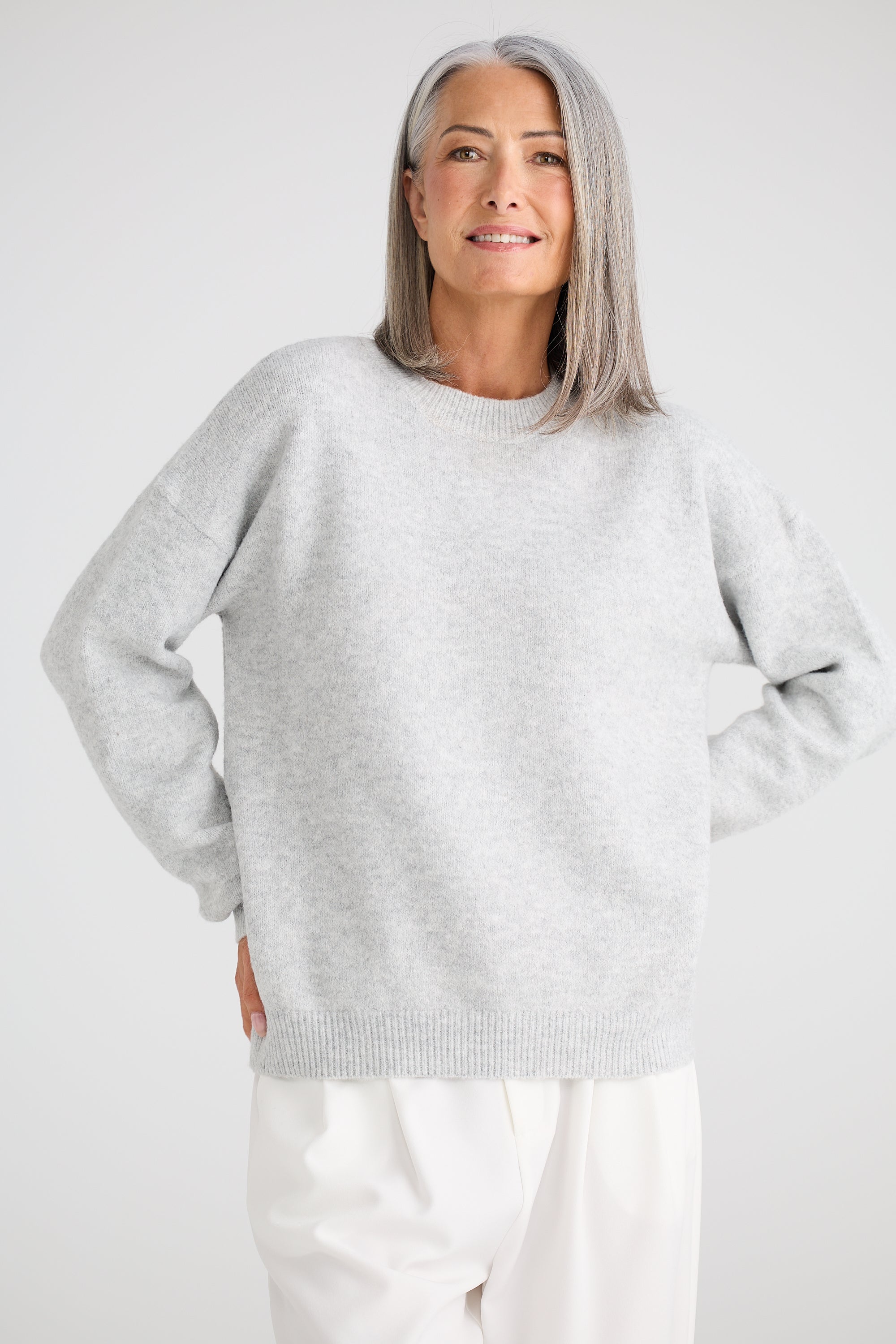Image of Woman wearing a Brave and True light grey sweater and white pants against a plain background
