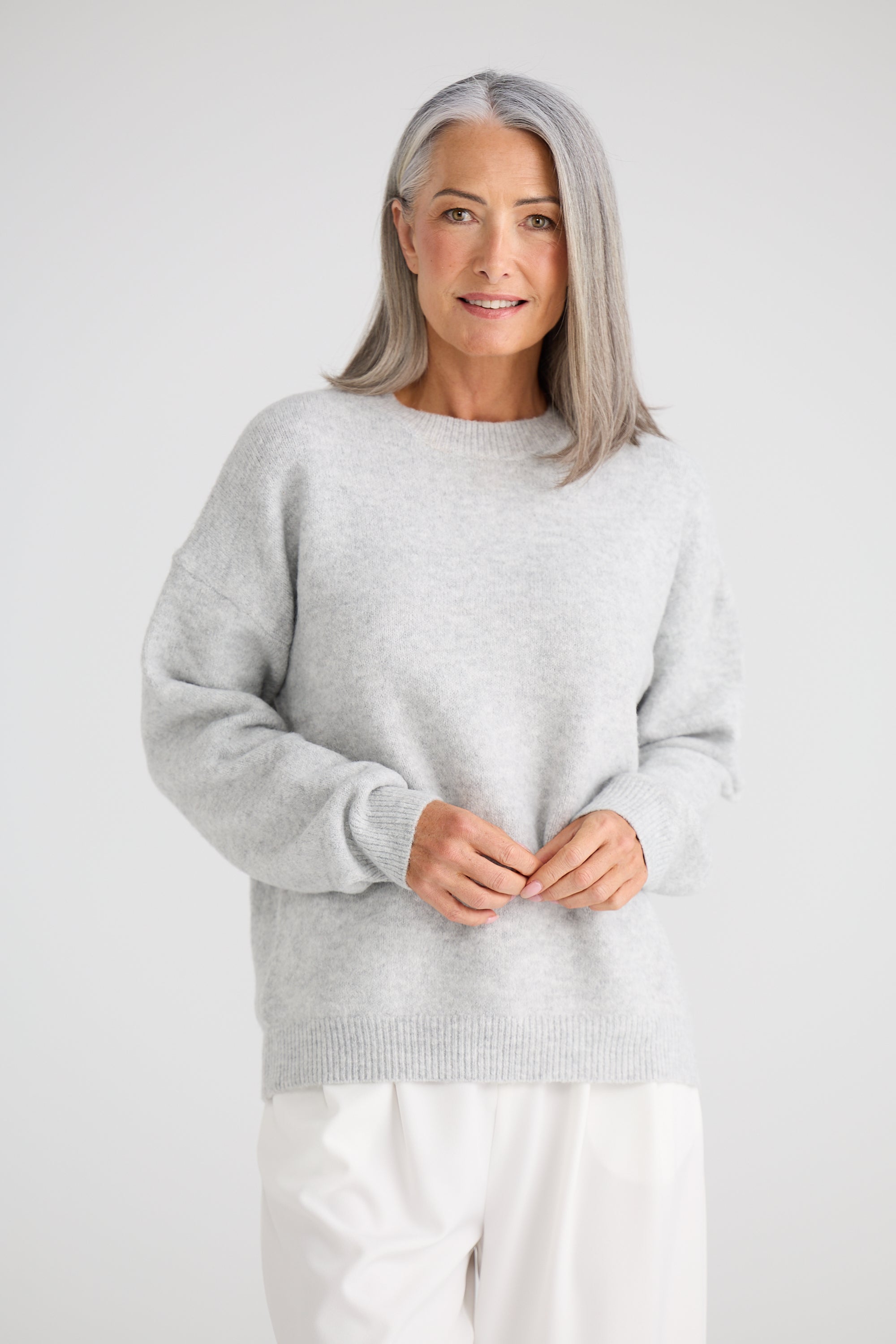 Image of Woman wearing a Brave and True light grey sweater and white pants against a plain background