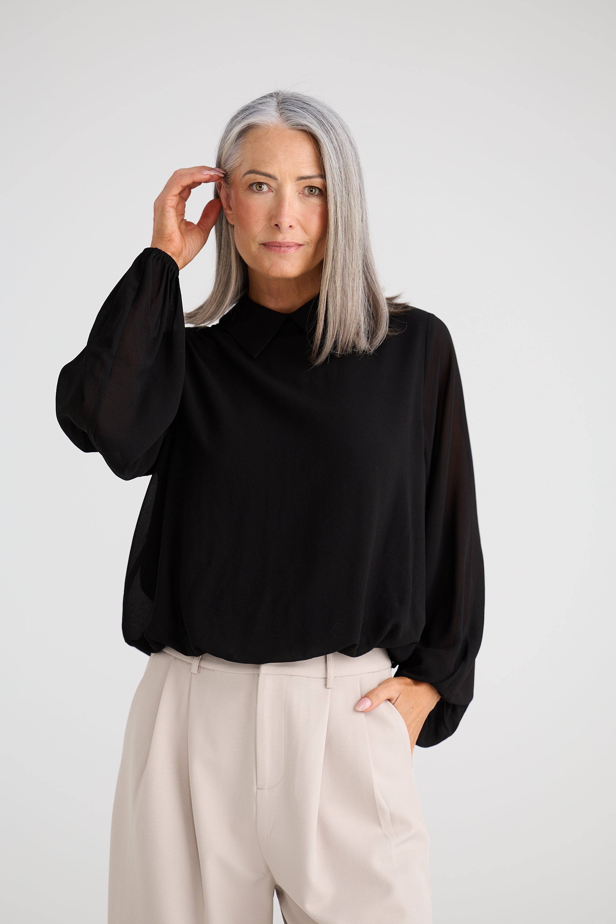 Collection of Woman wearing a Brave and True black blouse and beige pants against a white background in a gallery layout