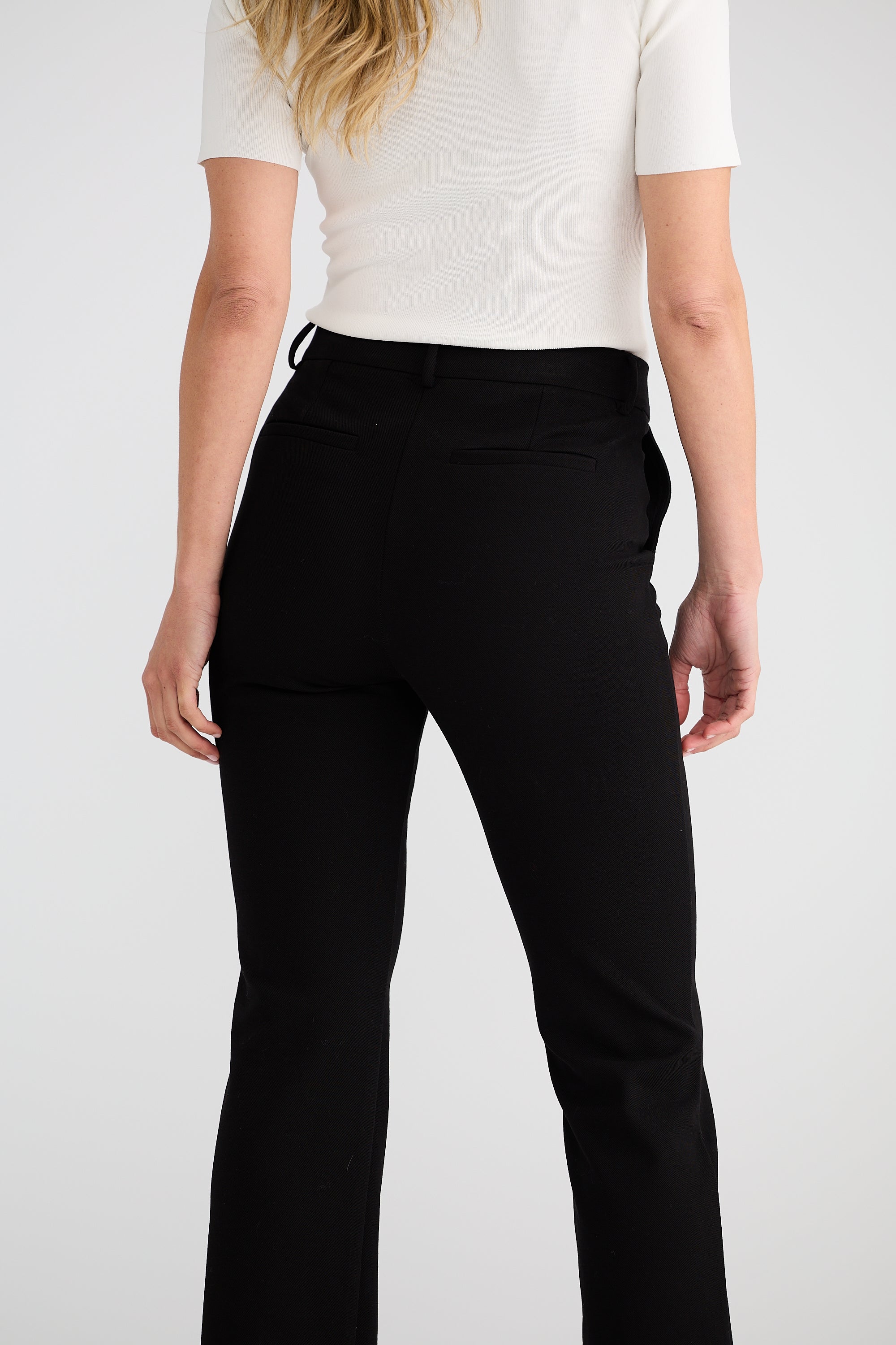 Image of Woman wearing Brave and True black pants and a white top on a plain background